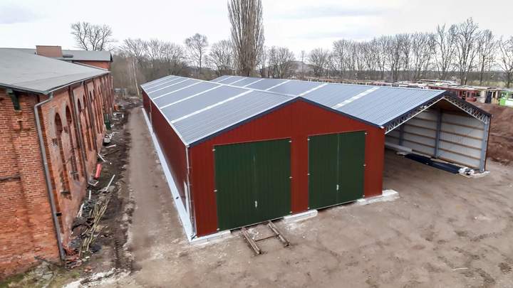 Die Satteldachhalle ist von außen in den Farben Rot und Grün gehalten.